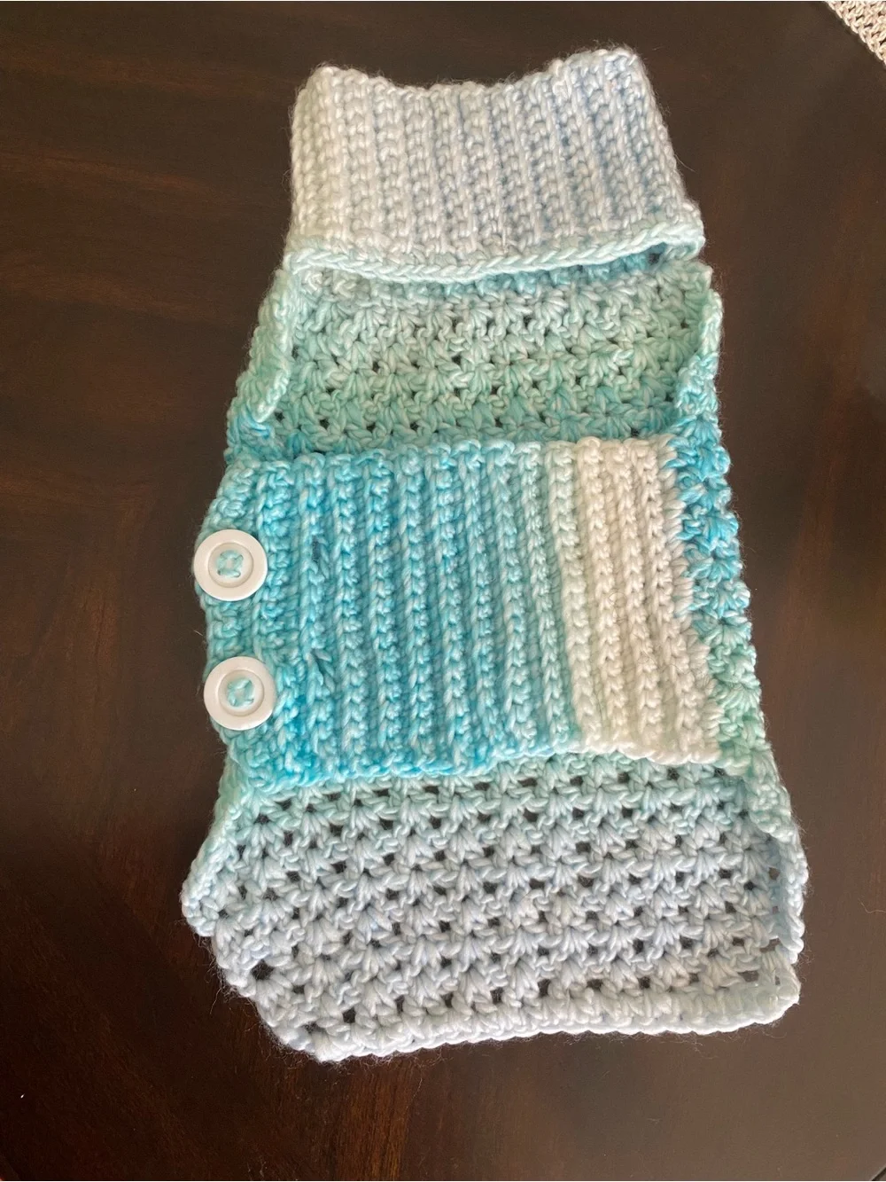 Hand-crocheted light blue dog sweater with buttons.